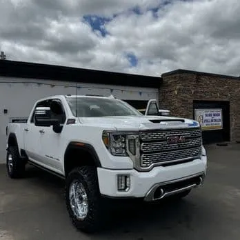 Clean lifted white GMC Denali truck outside the shop